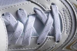 Teil von ein Weiß Sneaker mit Schnürsenkel. ein Fragment von Leder Schuhe. foto