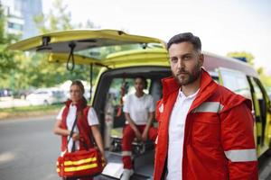 jung Mann, Sanitäter Stehen Rückseite von das Krankenwagen. Sanitäter durch das Krankenwagen. zwei Sanitäter Kommen aus von Krankenwagen foto