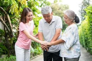 glücklich Familie Gehen zusammen im das Garten. alt Alten mit ein Gehen Stock zu Hilfe gehen Gleichgewicht. Konzept von Liebe und Pflege von das Familie und Gesundheit Versicherung zum Familie foto