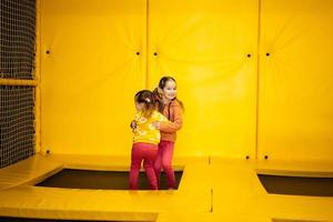 Geschwister Springen auf Trampolin beim Gelb Spielplatz Park. Schwestern im Bewegung während aktiv Unterhaltungen. foto