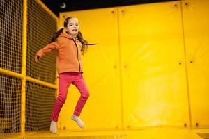 wenig Mädchen Kind Springen auf Trampolin beim Gelb Spielplatz Park. Kind im Bewegung während aktiv Unterhaltungen. foto