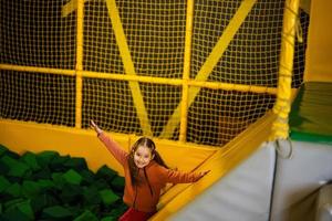 wenig Mädchen Kind rutschen zu Grün Sanft Würfel beim Gelb Spielplatz Park. Kind im aktiv Unterhaltungen. foto