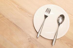 leeren Teller mit Silber Besteck auf hölzern Hintergrund. leeren Teller Löffel und Gabel auf das hölzern Tisch. foto