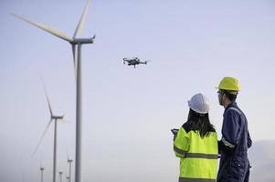 zwei Ingenieure Arbeiten und halten das Bericht beim Wind Turbine Bauernhof Leistung Generator Bahnhof auf Berg, Thailand Leute, Techniker Mann und Frau diskutieren Über Arbeit ,verwenden Drohne Aussicht von hoch Winkel foto