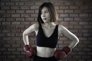 asiatisch schön Frau tragen Handschuh Boxen im das Fitnessstudio foto
