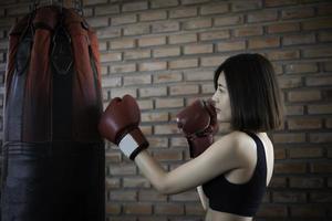 asiatisch schön Frau tragen Handschuh Boxen im das Fitnessstudio foto