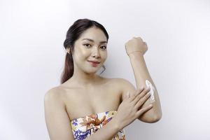 Haut Pflege Produkte Konzept. asiatisch Frau bewirbt sich feuchtigkeitsspendend Lotion auf Körper nach Dusche, Stehen eingewickelt im Handtuch, abgeschnitten Bild foto