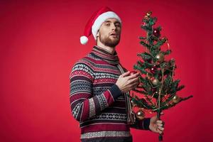 Mann im Neu Jahre Kleider Weihnachten Baum im Hände Spielzeuge Urlaub Emotionen foto