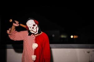 asiatisch gut aussehend Mann tragen Clown Maske mit Waffe beim das Nacht Szene, Halloween Festival Konzept, Schrecken unheimlich Foto von ein Mörder im Orange Tuch, böse Clown Charakter