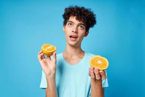 froh Mann im Blau T-Shirt mit Orangen im Hände Studio isoliert Hintergrund foto