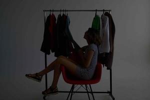 heiter Frau Sitzung auf das rot Stuhl in der Nähe von das Kleiderschrank isoliert Hintergrund foto