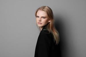 jung ausdrucksvoll schön blond Fachmann Modell- posieren isoliert im Studio Dressing im schwarz Jacke sieht aus beim Kamera. Mode minimalistisch Konzept foto