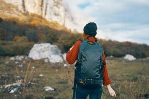 ein Reisender im ein Sweatshirt und ein Hut ist ruhen im das Berge im Natur und ein Rucksack auf ihr zurück foto