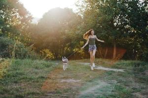 Frau und ihr heiser Hund glücklich Laufen durch das Gras im Natur im das Park Lächeln mit Zähne fallen gehen mit Haustier, Reisen mit ein Hund Freund foto