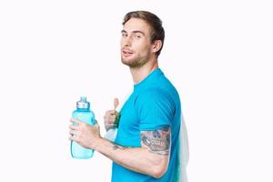 Sport Mann mit tätowieren auf seine Arm trainieren Wasser Flasche abgeschnitten Aussicht Licht Hintergrund foto