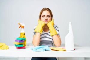 Frau Sitzung beim das Tabelle Gummi Handschuhe Reinigung Hausarbeit Waschmittel Bedienung foto