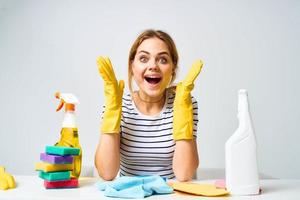 Frau Sitzung beim das Tabelle Waschmittel Lumpen Schwämme Zuhause Pflege Innere Licht Hintergrund foto