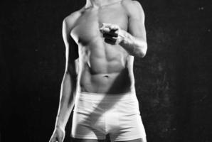 Bodybuilder mit ein gepumpt oben Körper im Weiß Höschen posieren dunkel Hintergrund foto