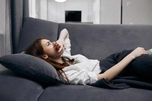 Frau halten ihr Hand auf ihr Gesicht Lügen auf das Couch versteckt hinter ein Decke Gefühl nicht wohl foto