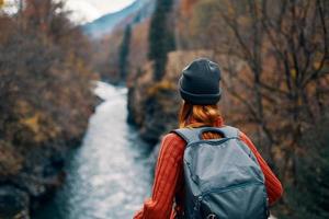 Frau mit Rucksack bewundert das Fluss im das Berge Natur Reise foto