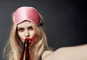 betrunken blond Mädchen mit ein Flasche von Bier Gesten mit ihr Hände und ein hell bilden Sucht Modell- foto