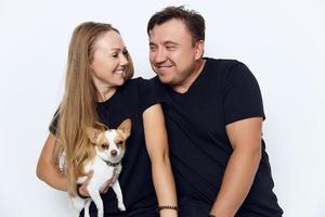 verheiratet Paar im schwarz T-Shirts wenig Hund Freude foto