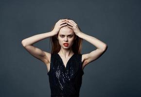 emotional Frau berührt ihr Kopf mit Hände und schwarz Kleid Modell- grau Hintergrund foto