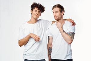 zwei heiter freunde im Weiß T-Shirts Umarmung Emotionen foto