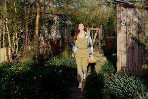 Frau Spaziergänge glücklich durch Garten mit Vogel Feeder nach Fütterung Hühner auf ihr Bauernhof foto