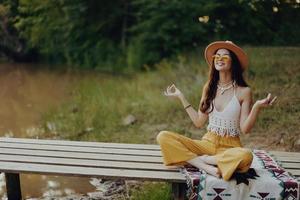 ein Hippie Frau meditieren im Natur im das Lotus Position im das Sonnenuntergang Licht foto