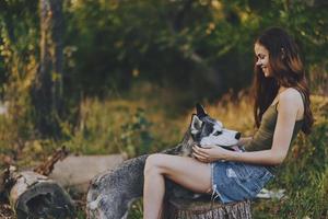 Frau und ihr heiser Hund glücklich spielen draußen im das Park unter das Bäume Lächeln mit Zähne im das Herbst gehen mit ihr Haustier foto