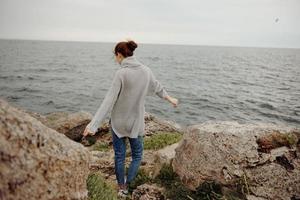 ziemlich Frau Pullover wolkig Meer bewundern Natur Lebensstil zurück Aussicht foto