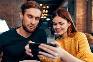 jung Paar Mann und Frau im ein Restaurant Bestellung Essen und Handy, Mobiltelefon Telefon im Hand Beleuchtung foto