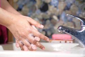 Nahaufnahme der Person, die Hände an einem Waschbecken wäscht foto