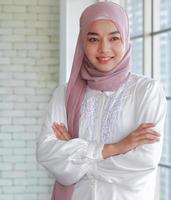 schöne muslimische asiatische Geschäftsfrau steht lächelnd mit Glück im Amt