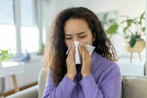 krank verzweifelt asiatisch Frau hat Grippe. Schnupfen, kalt, Krankheit, Allergie Konzept. ziemlich krank Frau hat Laufen Nase, reibt Nase mit Taschentuch. Niesen weiblich. Brünette Niesen im ein Gewebe foto