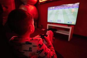 Junge Spieler abspielen Gamepad Fußball Video Spiel Konsole im rot Spielen Zimmer. foto