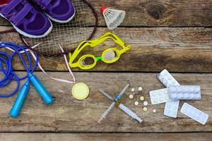 Sport Ausrüstung Schläger, überspringen Seil, Schwimmen Brille, Turnschuhe, Sport Medaille und Medikamente auf hölzern Hintergrund. getönt Bild foto