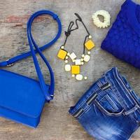 Damen Herbst Kleidung und Zubehör Blau Pullover, Jeans, Handtasche, Perlen auf hölzern Hintergrund. foto