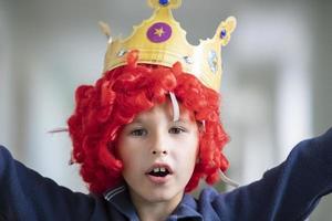 Kind im ein rot Perücke und ein Krone. Clown Junge foto