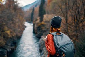 Frau mit Rucksack bewundert das Fluss im das Berge Natur Reise foto