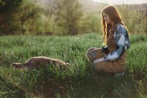 ein Frau spielen im das Park mit ihr wenig Hund im das Sommer- Sonnenuntergang Licht und lächelnd foto