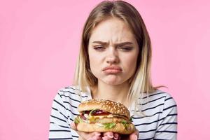 süß blond Mädchen im gestreift T-Shirt Hamburger Nahansicht schnell Essen Lebensstil foto