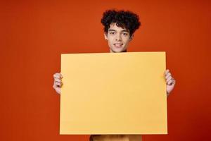 emotional Mann mit lockig Haar Gelb Poster im Hände foto