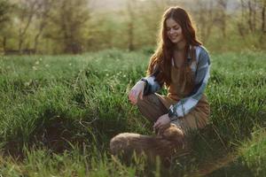 jung rothaarig Frau spielen im Natur mit ihr Hund im sonnig Park beim Sonnenuntergang im Sommer- foto