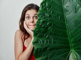 ziemlich Frau überrascht aussehen Palme Blatt exotisch Nahansicht foto