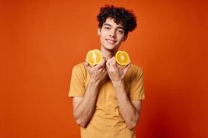 Kerl mit lockig Haar Orangen im Hände Obst Spaß rot Hintergrund foto