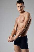 sportlich Mann im schwarz kurze Hose auf nackt Körper grau Hintergrund Muskel Bodybuilding foto