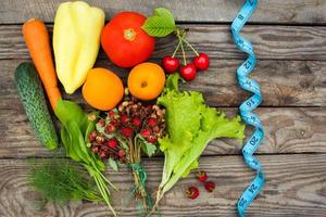 Früchte, Gemüse und im messen Band im Diät auf hölzern Hintergrund foto