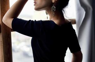 schön Frau im ein schwarz Kleid in der Nähe von das Fenster posieren elegant Stil foto